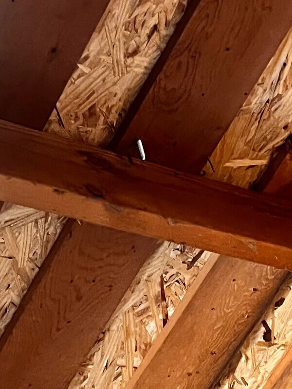 A view of wooden rafters in a garage with visible bracket locations.