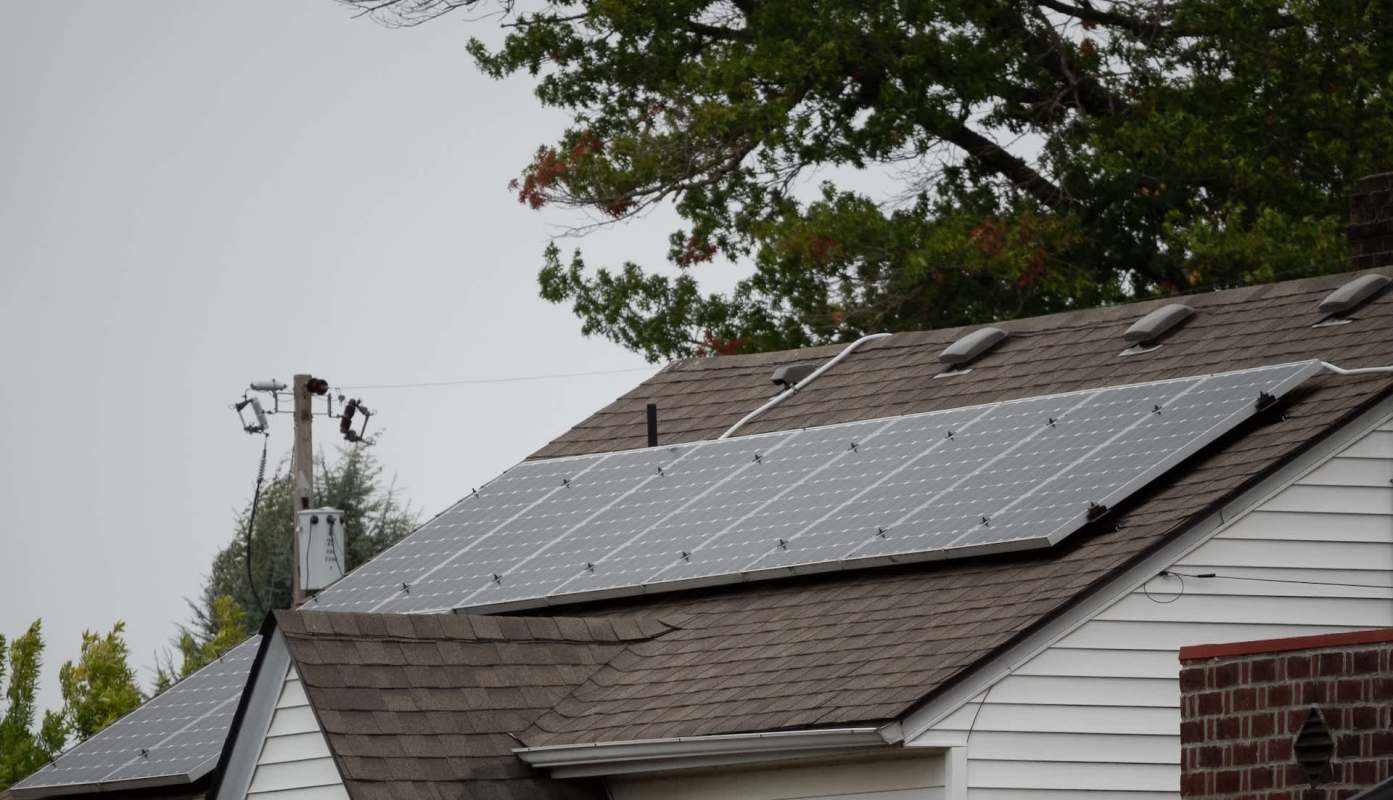 A house roof with solar panels and a power pole in the background.