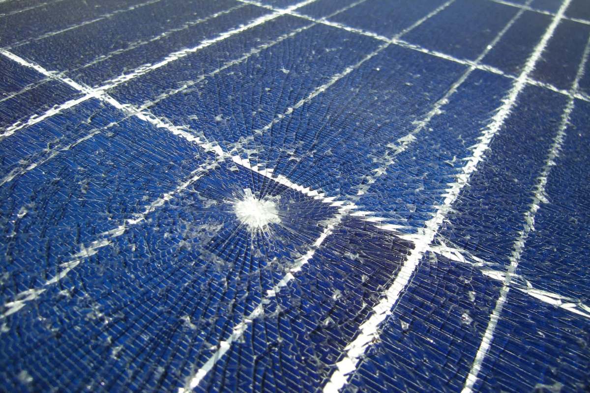 A damaged solar panel with cracked blue glass and visible grid lines.