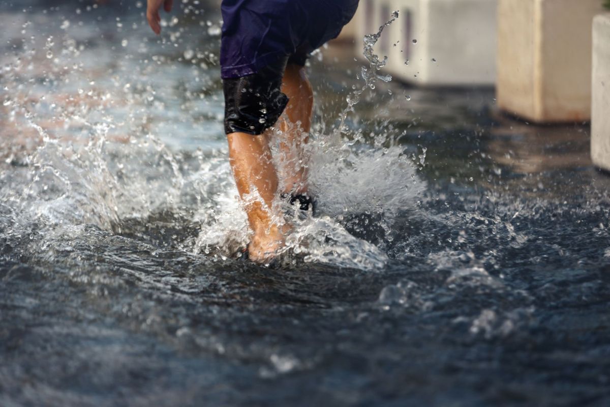 A person running on a flooded road.