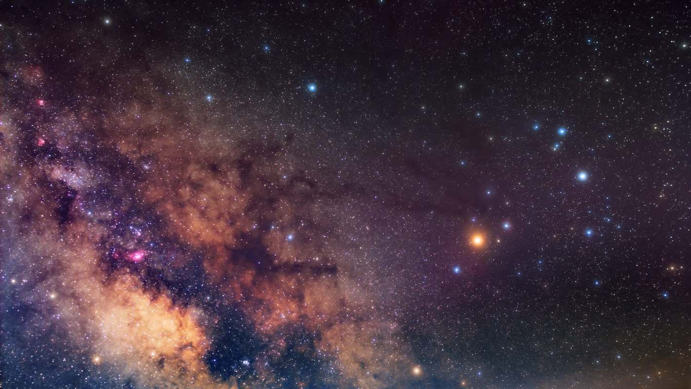A view of a starry night sky with various stars and nebulae.