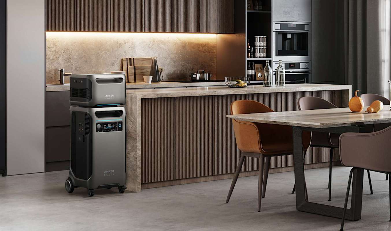 A kitchen with a gray air purifier, modern cabinetry, and a dining table with chairs and fruit.