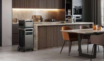 A kitchen with a gray air purifier, modern cabinetry, and a dining table with chairs and fruit.