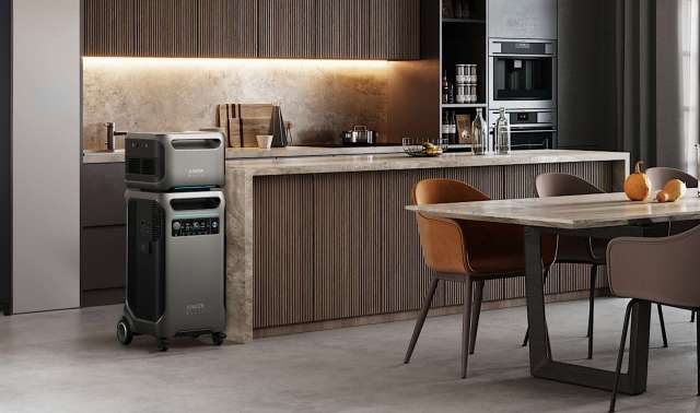 A kitchen with a gray air purifier, modern cabinetry, and a dining table with chairs and fruit.