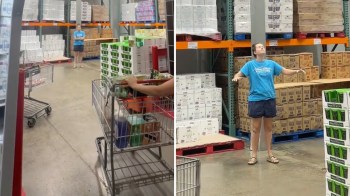 A grocery store aisle with shopping carts and stacked boxes of items, featuring a woman standing with arms outstretched.
