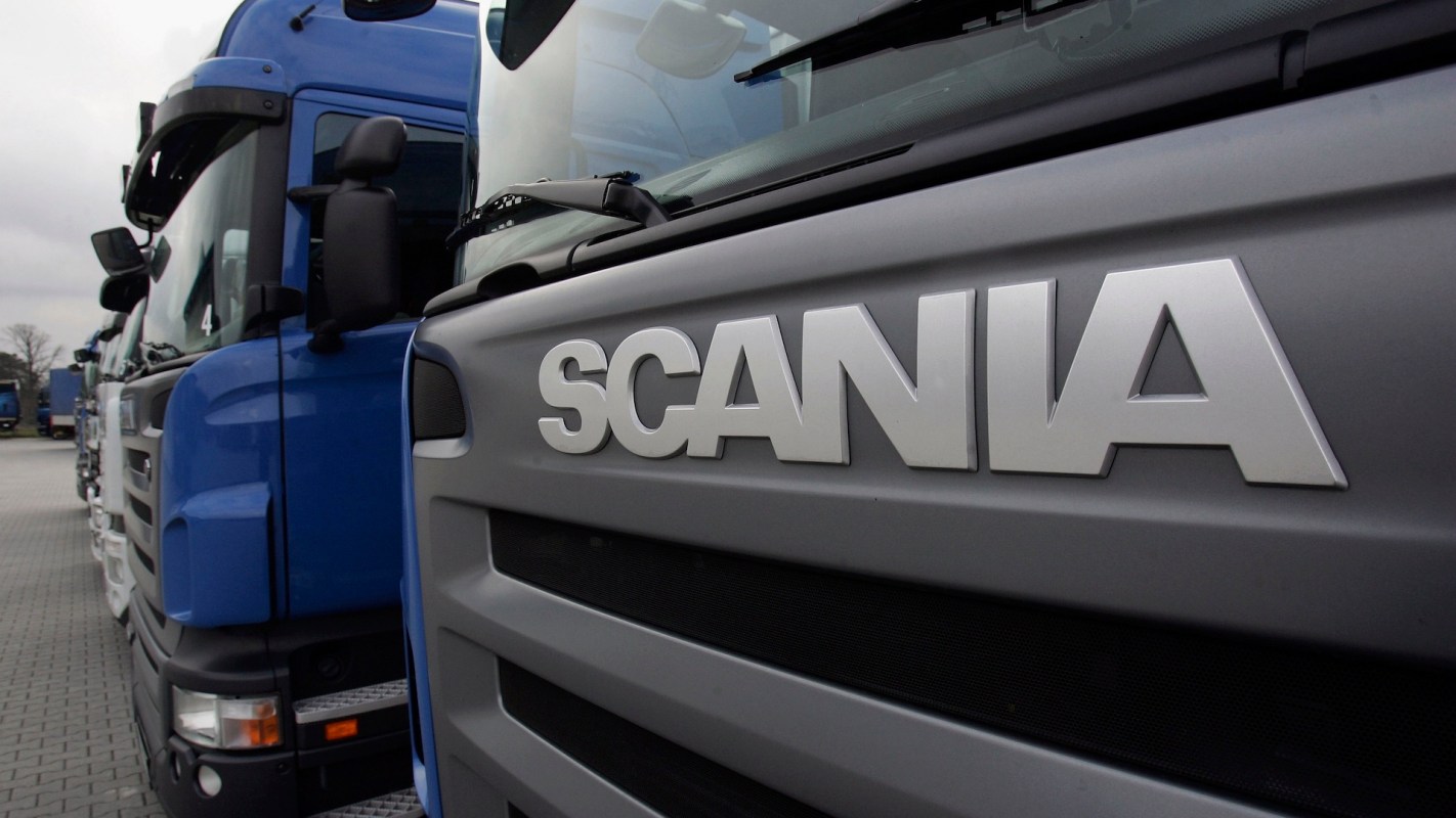 A row of Scania trucks parked with a focus on the Scania logo on the front of one truck.