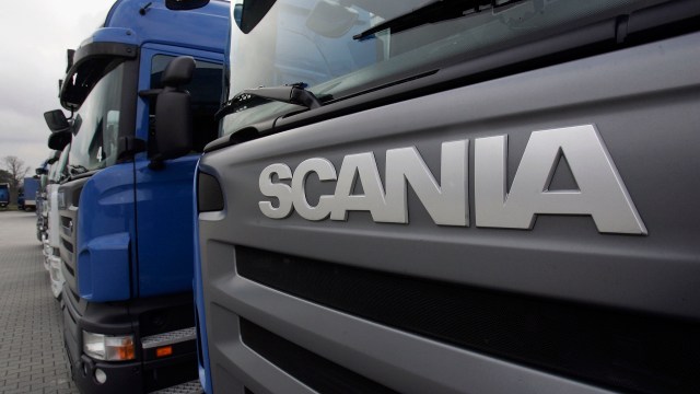 A row of Scania trucks parked with a focus on the Scania logo on the front of one truck.