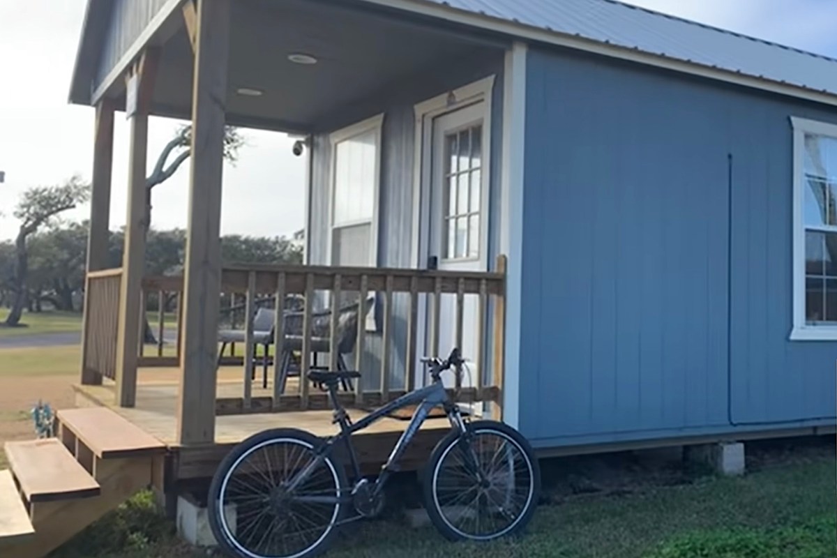 A blue house with a porch and a bicycle parked nearby.