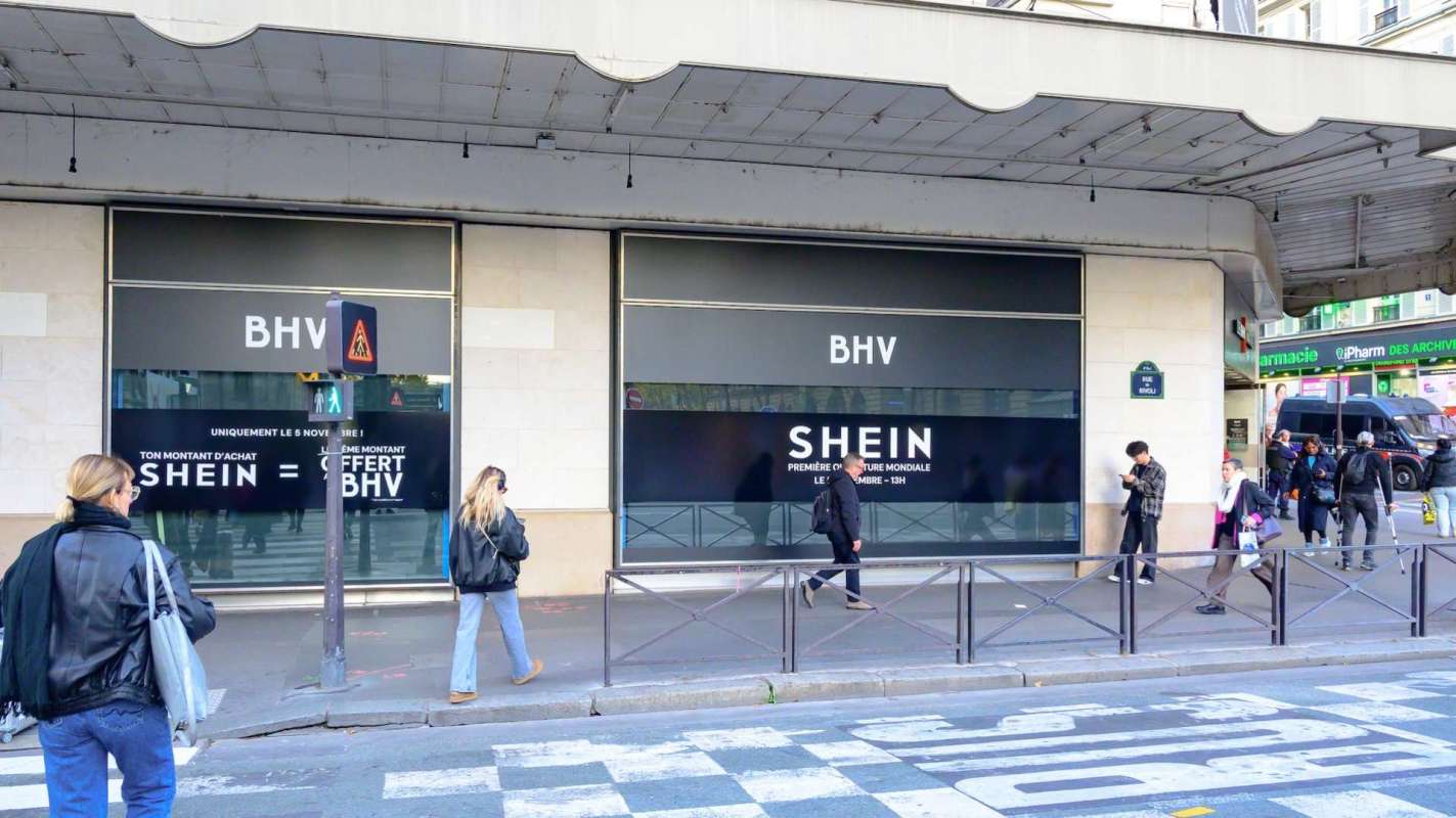 A storefront with "BHV" and "SHEIN" signage, with people walking by on a city street.