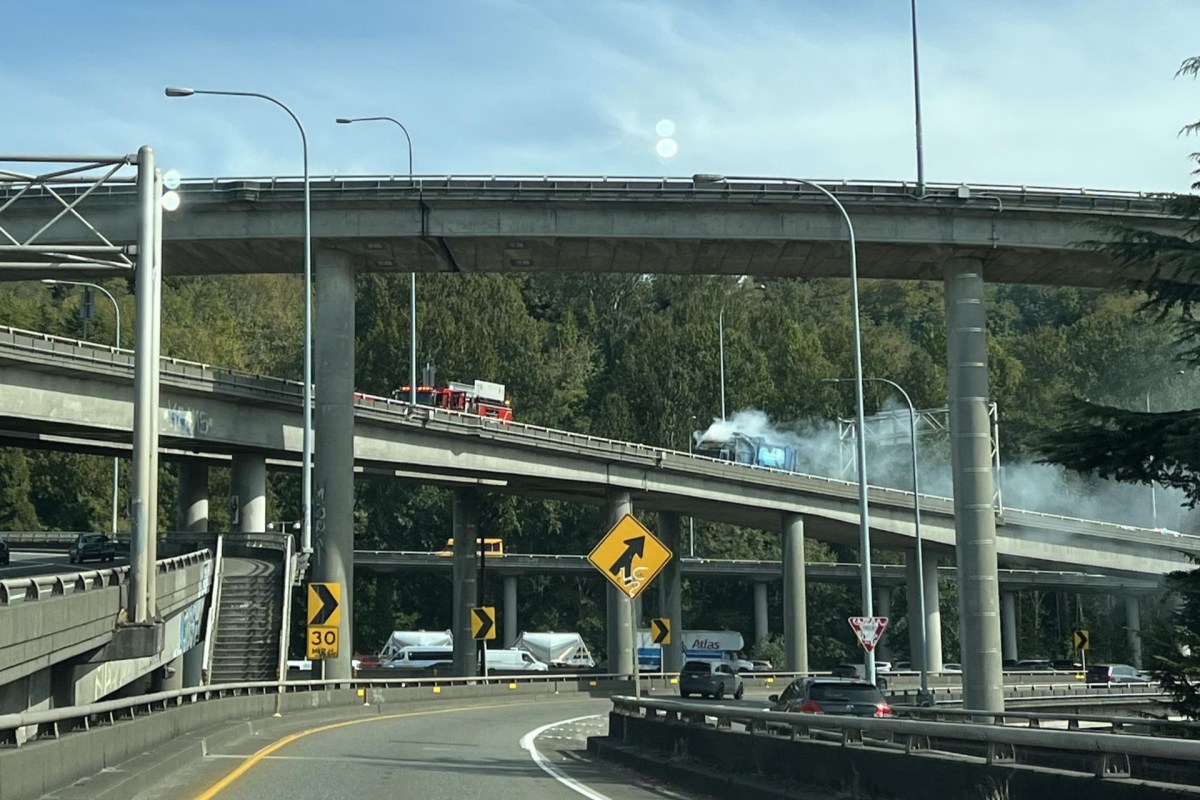 An interstate exchange with a truck driving down the road with smoke coming from it