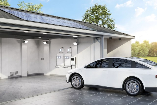 A home with solar panels on the roof and an electric vehicle charger in the garage with an EV out front