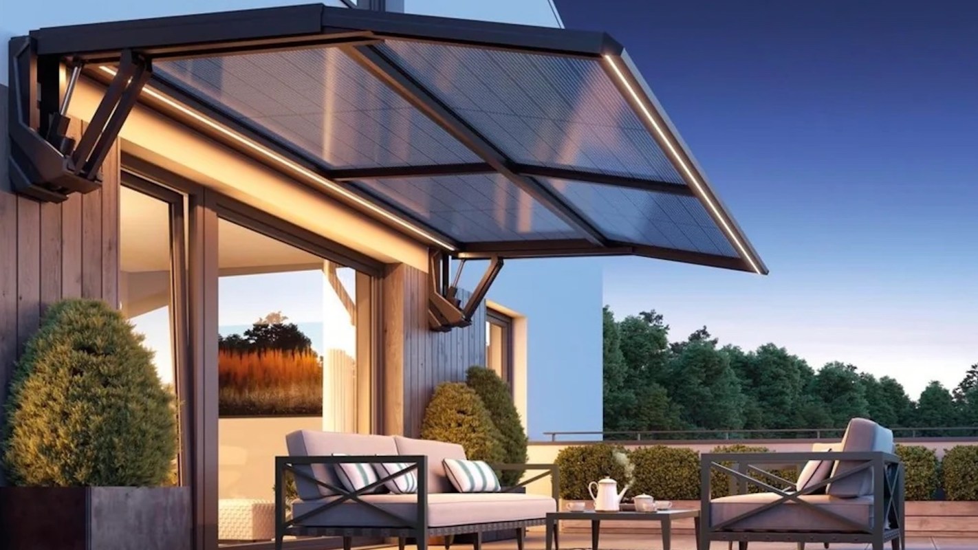 A modern patio with seating and a solar-powered awning, surrounded by greenery.