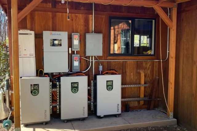 A wall-mounted electrical system with batteries and control units in a wooden structure.