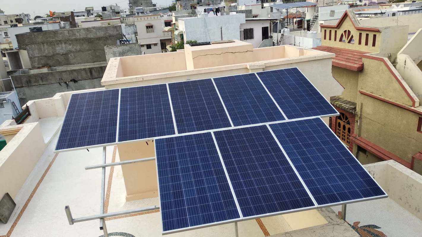 Solar panels installed on a rooftop with surrounding buildings in the background.