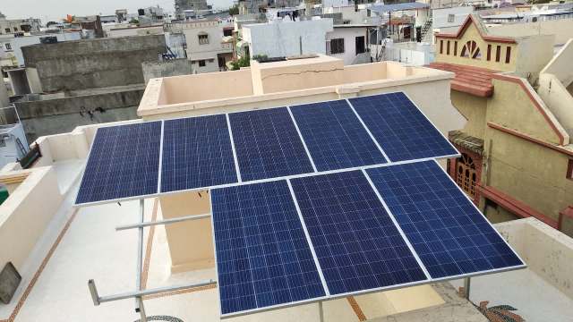 Solar panels installed on a rooftop with surrounding buildings in the background.