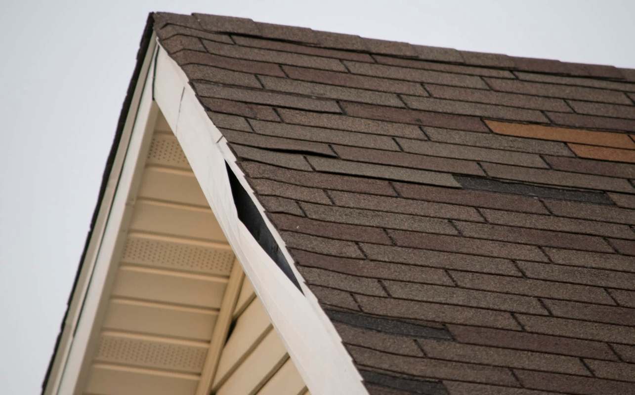A roof with asphalt shingles showing a visible gap and protective covering.