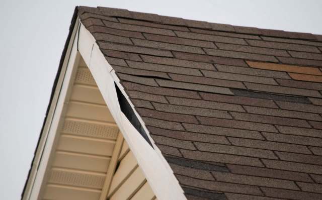 A roof with asphalt shingles showing a visible gap and protective covering.