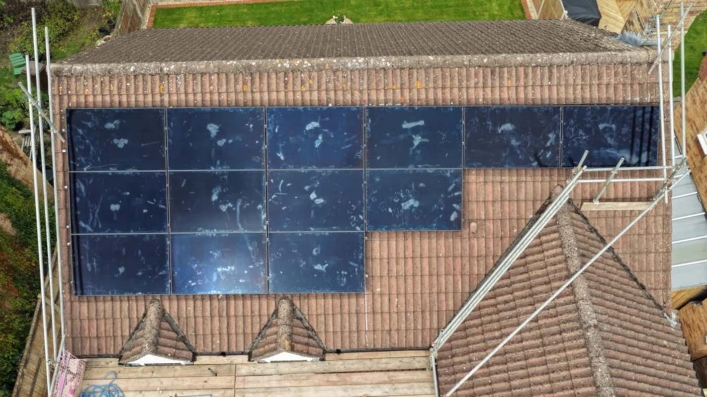Solar panels installed on a sloped roof, with scaffolding visible nearby.