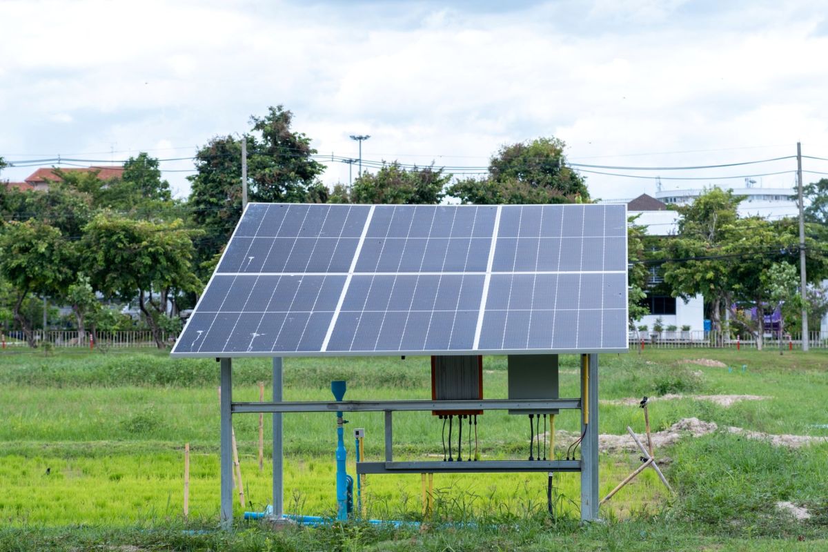 An angled solar panel stands in a grassy field