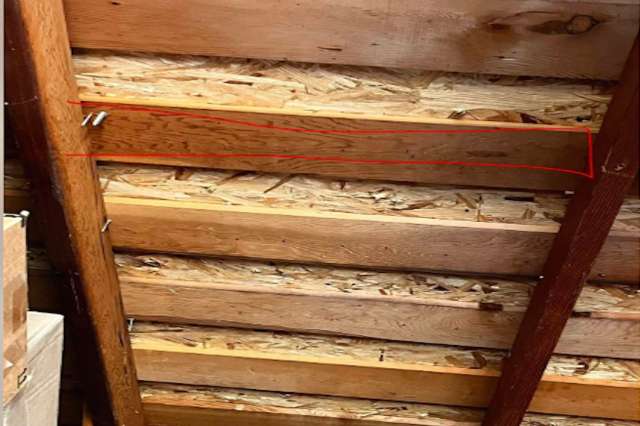 A view of wooden rafters in a garage with visible bracket locations.