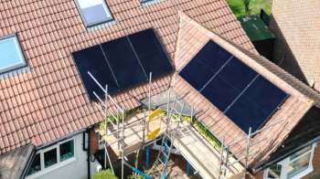A roof with solar panels and scaffolding around a house.