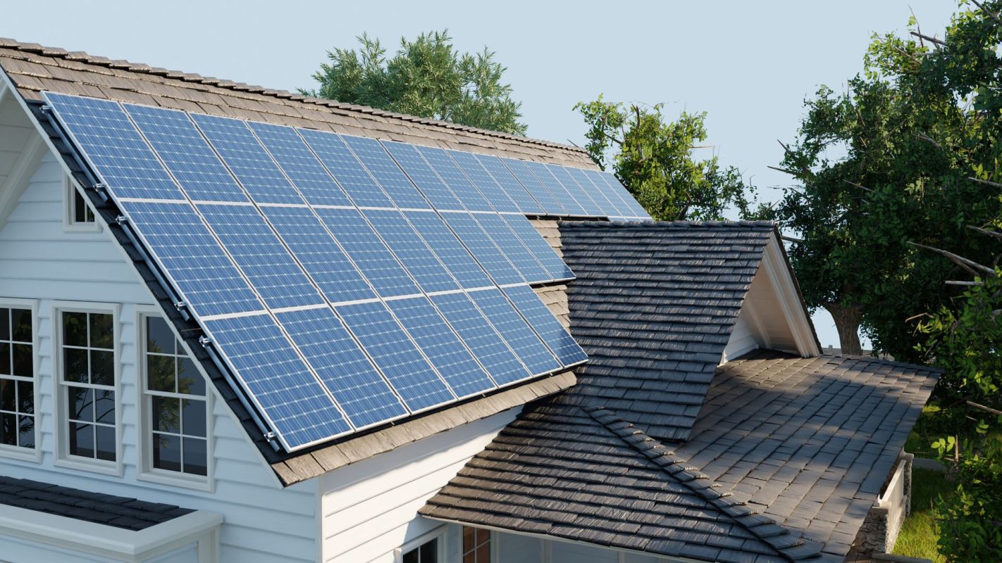 Solar panels are installed on the roof of a house surrounded by trees.