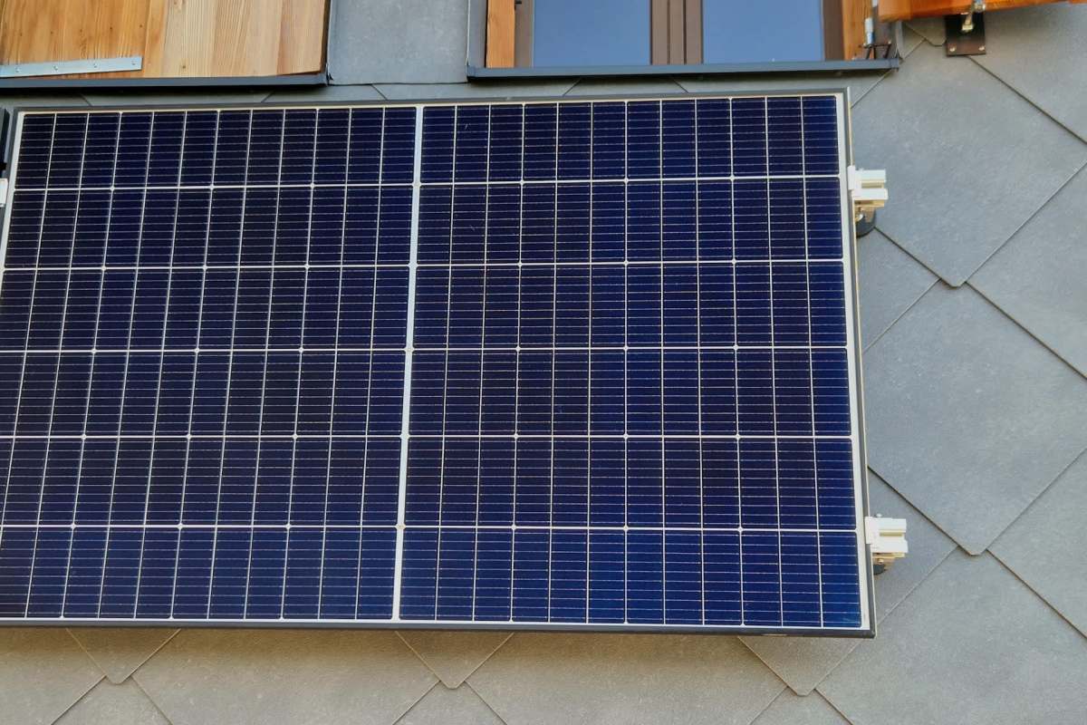 A solar panel mounted on a textured surface with wooden elements visible in the background.