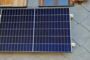 A solar panel mounted on a textured surface with wooden elements visible in the background.