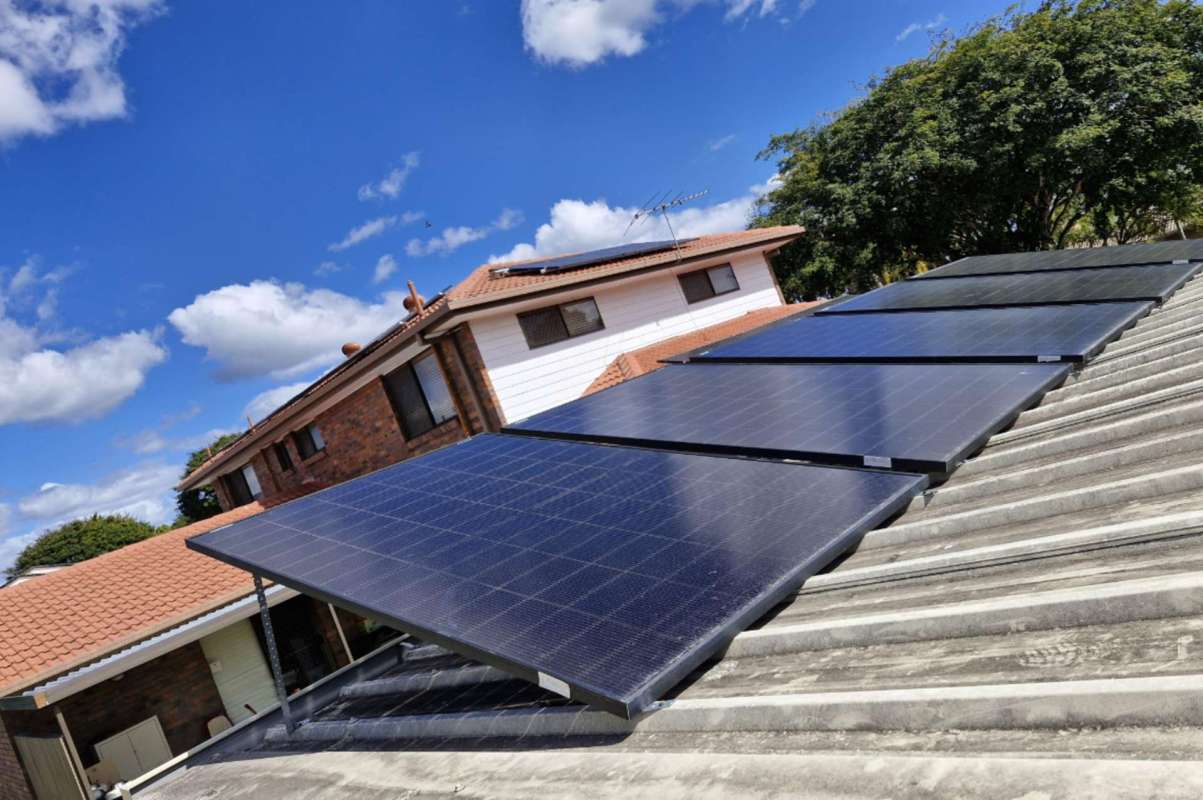 Solar panels installed on a roof under a partly cloudy sky.
