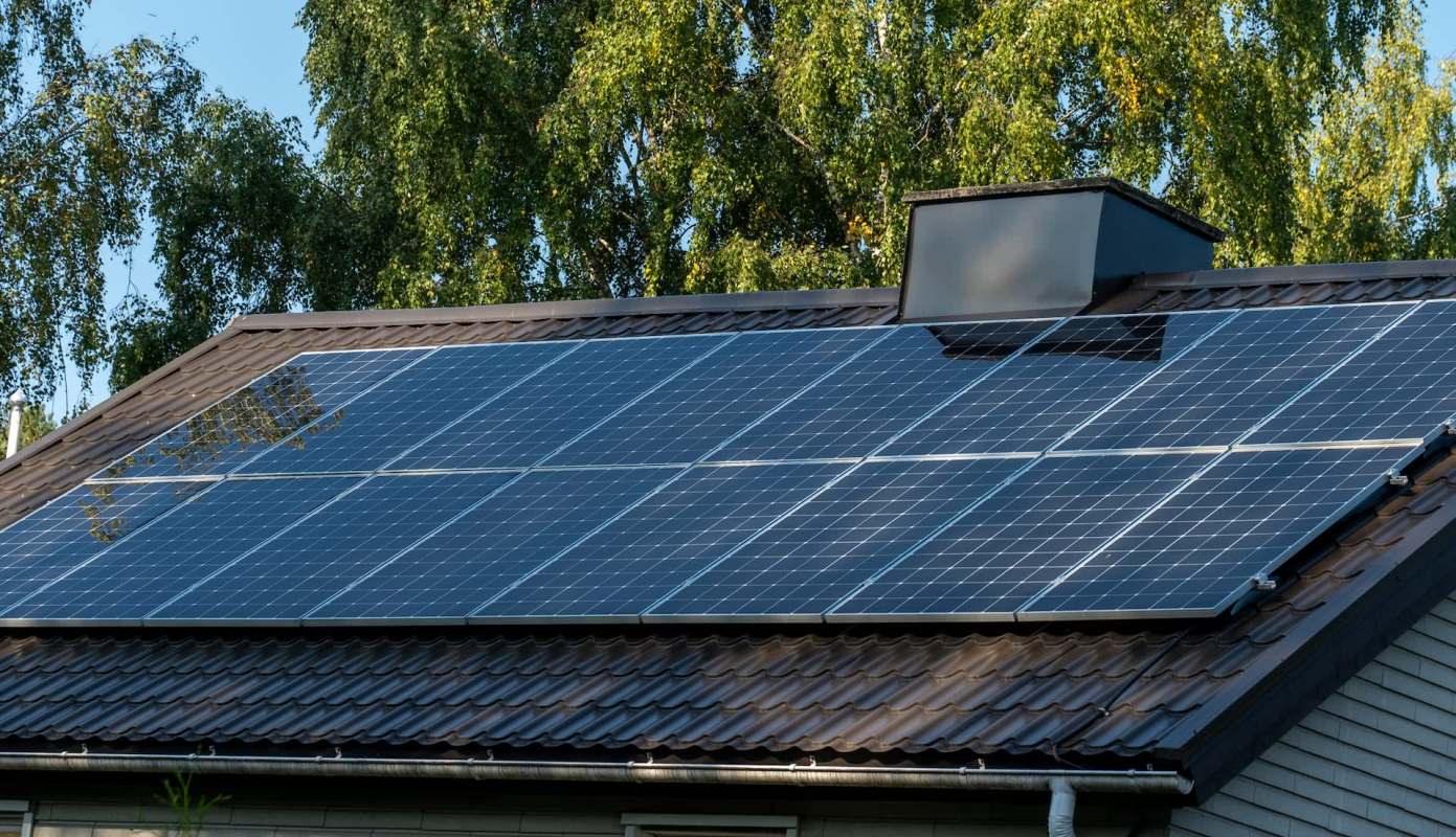 Solar panels installed on the roof of a building with trees in the background.