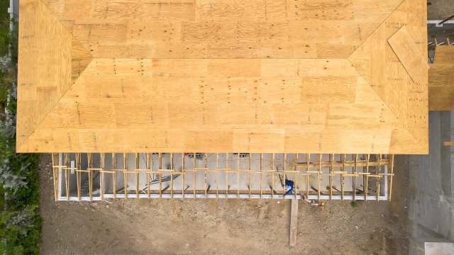 A wooden roof under construction with open framing and a gravel area below.
