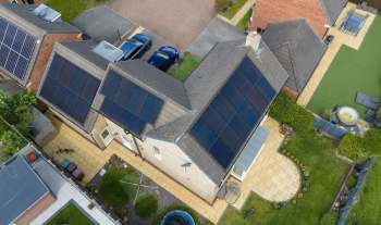 An overhead view of English houses with solar panels and landscaped gardens.