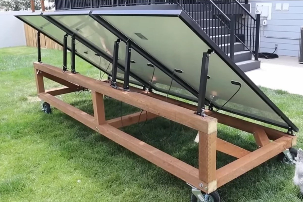 A mounted solar panel system on a wheeled wooden frame in a grassy area.