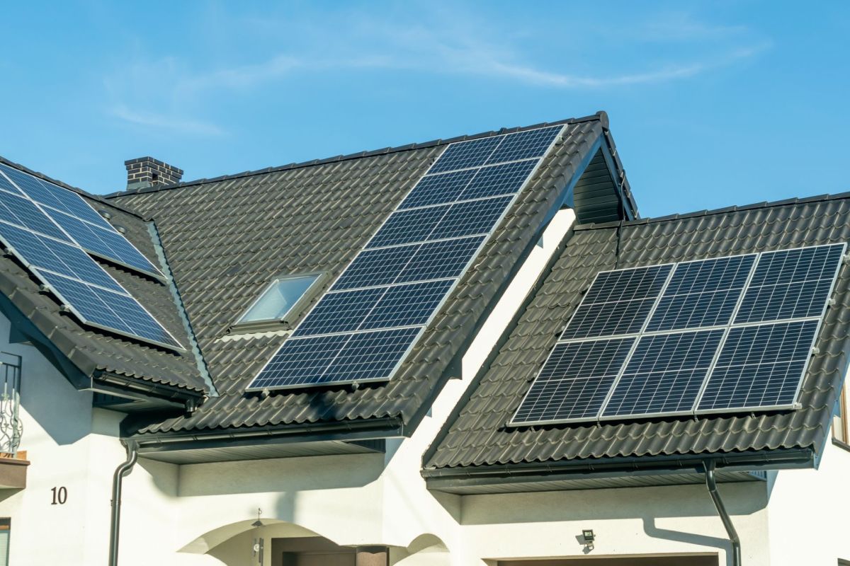 An array of solar panels sit on a rooftop of a house