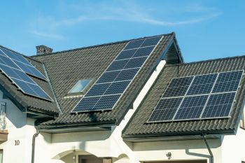 An array of solar panels sit on a rooftop of a house