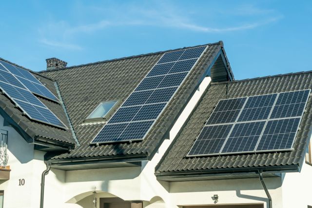 An array of solar panels sit on a rooftop of a house