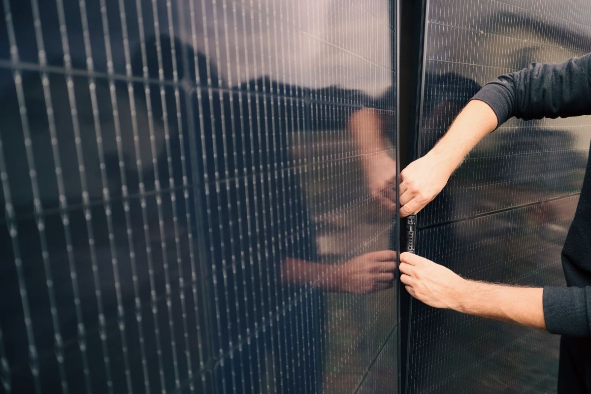 A person connecting two solar panels.