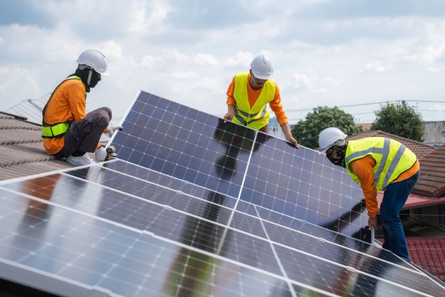 Workers installing solar panels on the roof of a house.