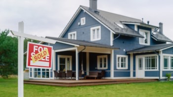 A house with a "Sold" sign in front of it.