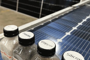 Solar panels behind bottles of solar panel materials.