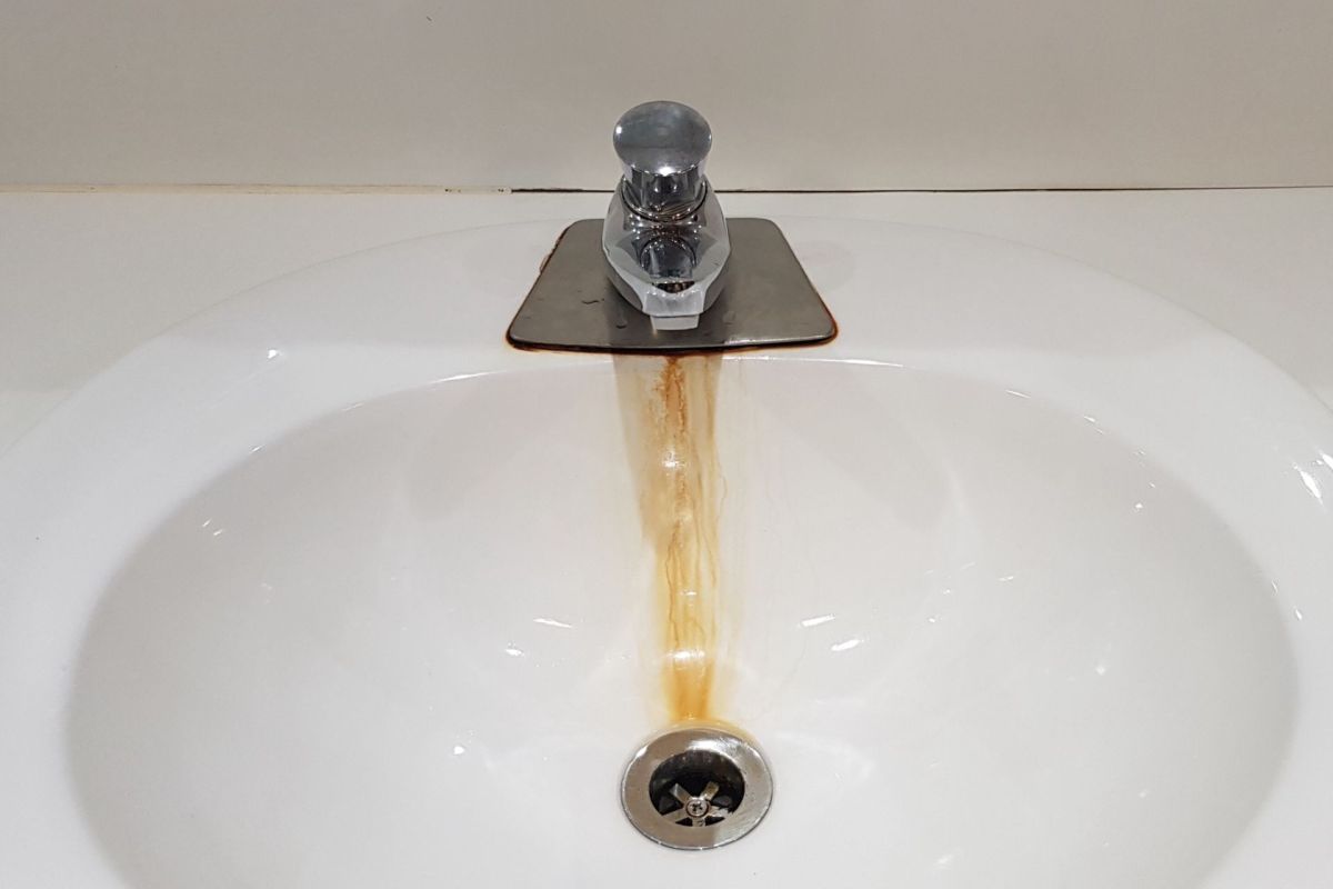 A white hand basin sink with faucet shows and orange stain from where the water runs
