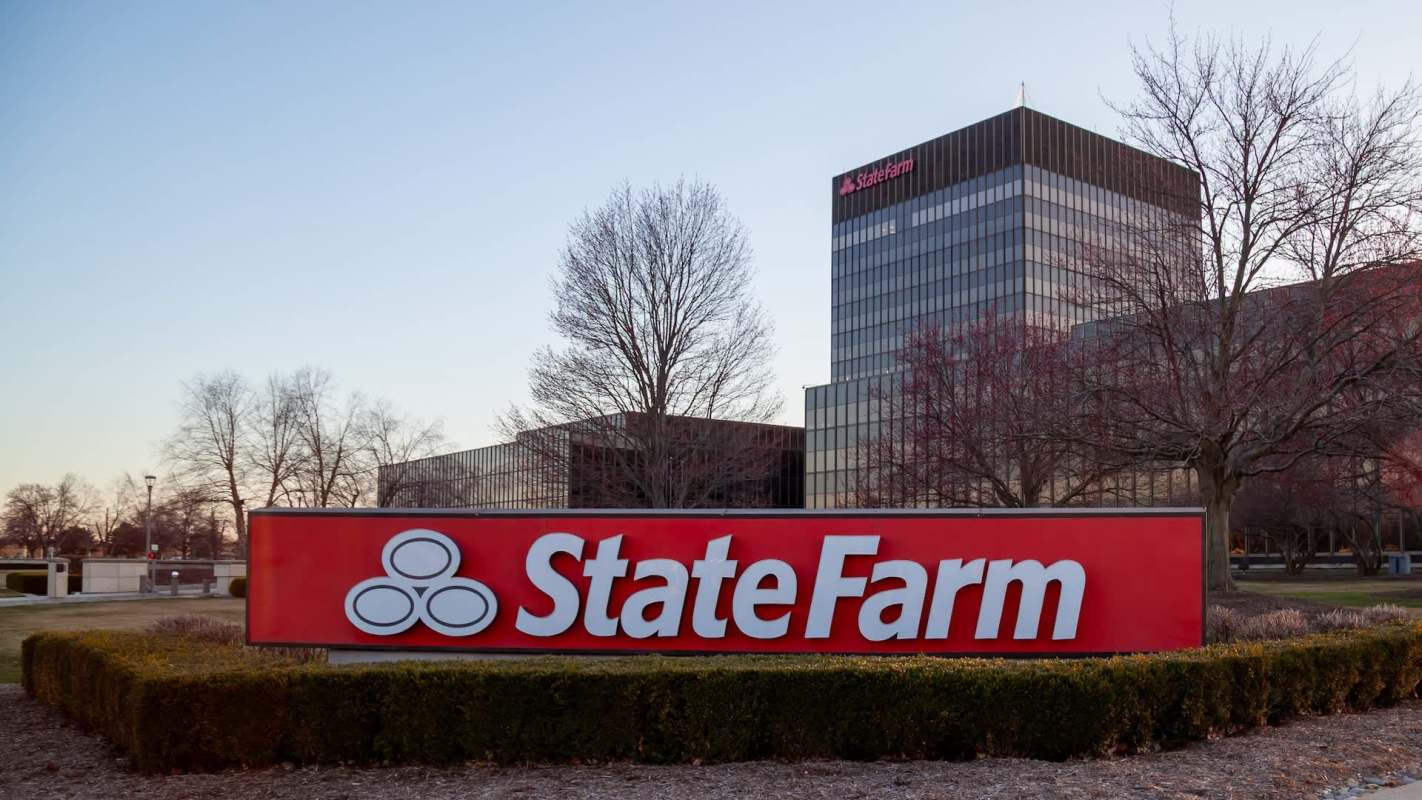 A State Farm sign in front of a modern office building with bare trees and shrubs.