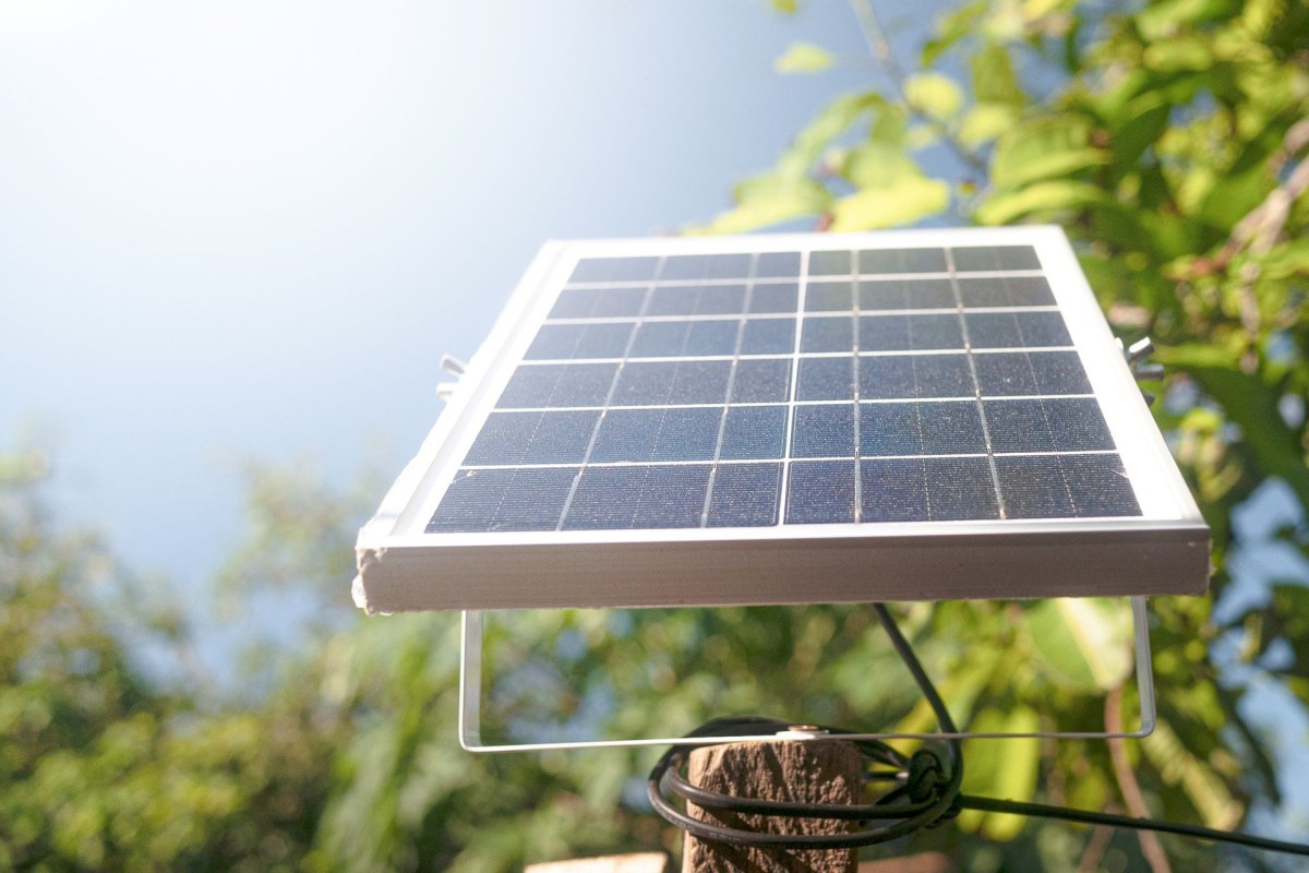A small solar panel is angled toward the sun outside
