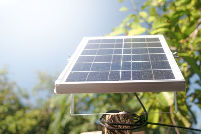 A small solar panel is angled toward the sun outside