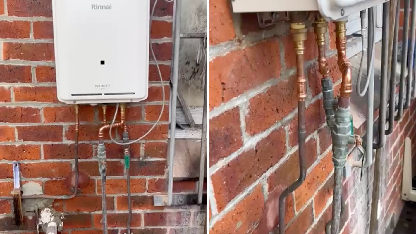 A wall-mounted Rinnai heating unit with connected pipes on a brick wall.