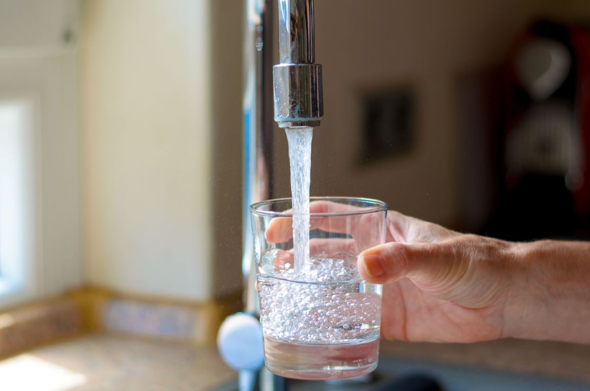 A person filling a glass with tap water.