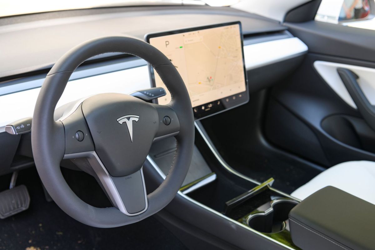 The interior of a Tesla model 3 including its steering wheel and center control panel console