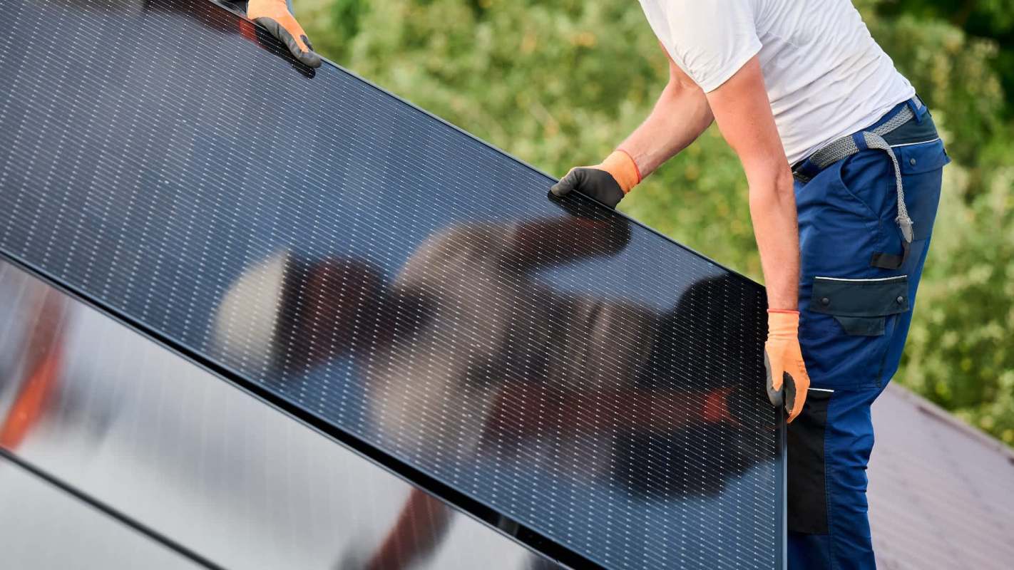 A person installs a solar panel on a roof.
