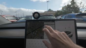 A man's hand reaches toward the center console displaying a map inside a Tesla