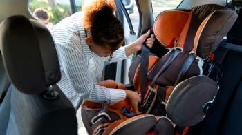 A person secures a car seat inside a vehicle.